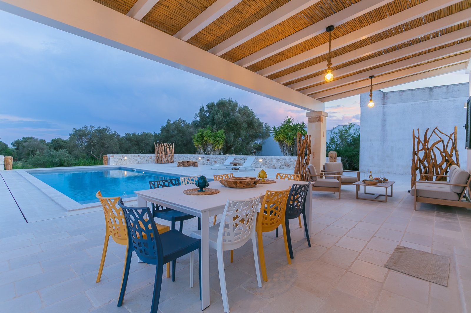 Table extérieure et piscine en soirée